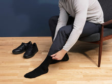 Load image into Gallery viewer, Man Putting On Black Sigvaris Casual Cotton Compression Socks